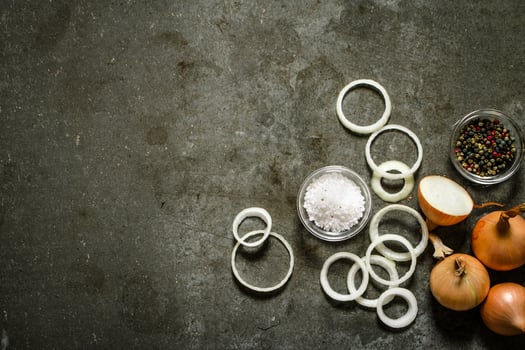 Onion rings and spices. On stone background. photo