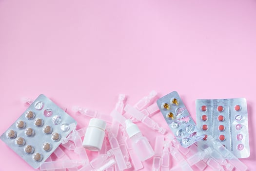 Medications and medical ampoules on pink background. photo