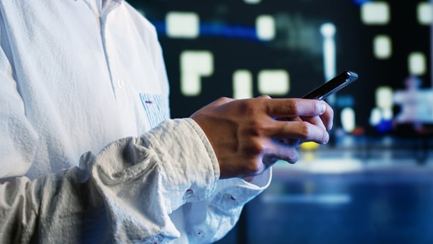 Close up shot of aimless man strolling around city streets at night, chatting with his buddies using smartphone in urban setting. Carefree person enjoying empty town with no cars, using mobile phone photo
