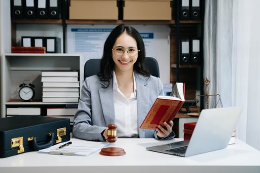 justice and law concept. Asian Female judge in a courtroom on wooden table and Counselor or Male lawyer working in modern office. photo