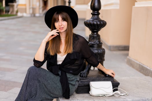 Confident stylish brunette woman   posing in  european city, walking on the street. Wearing casual outfit, black hat and blouse. Autumn fashion look. photo