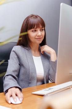 A brunette woman at a computer in the workplace. Business concept. photo