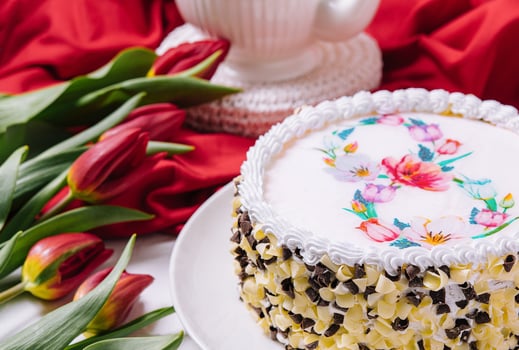 White cake decorated with cream near red tulips photo