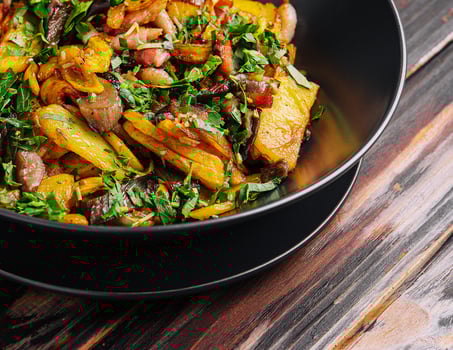 Fried potatoes with mushrooms on a black plate photo