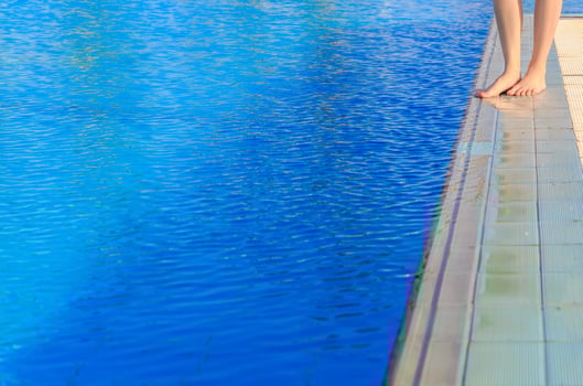 Young woman legs standing on border front of swimming pool photo