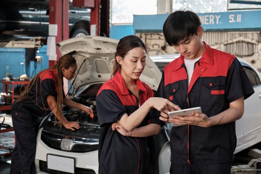 Two Asian professional mechanics, male supervisor engineer, and partner discuss and inspect repair work checklists at garage, service car maintenance, and fixing specialist occupations auto industry. photo