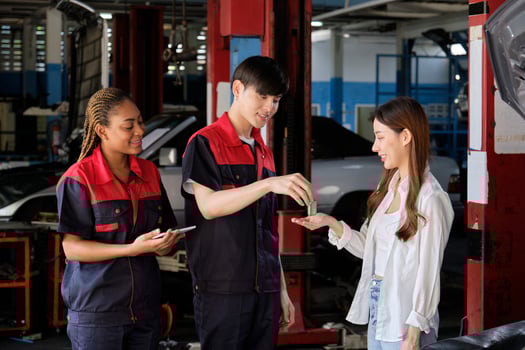 Asian female customer receives car key from automotive staff workers, quality guarantee with trust at maintenance garage, professional vehicle service center, ensuring fix checks, and repair industry. photo