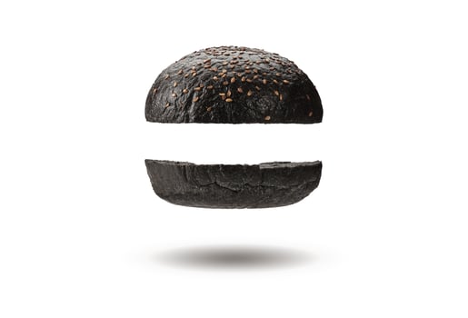 Flying and delicious, baked or grilled, two halves of black burger bun with sesame seeds. Isolated on white. Cooking, fast food. Close-up, copy space photo
