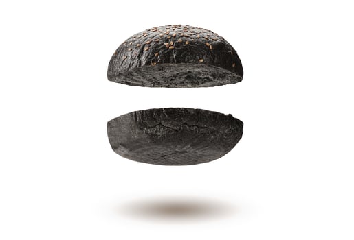 Flying, baked or grilled, cut in half black burger bun with sesame seeds isolated on white background. Cooking, fast food. Close-up, copy space photo