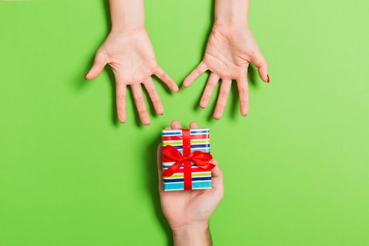 Top view of couple giving and receiving a gift on colorful background. Romantic concept with copy space photo