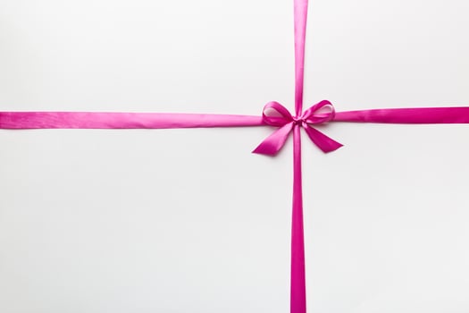 Top view of purple ribbon rolled and pink bow isolated on colored background. Flat lay with copy space photo
