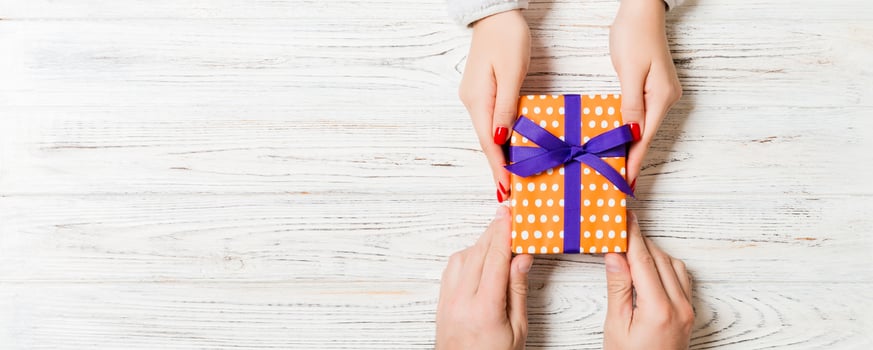 Top view of holding a gift in female and male hands on wooden background. Woman and man give and receive a present. Time for holiday concept with copy space photo