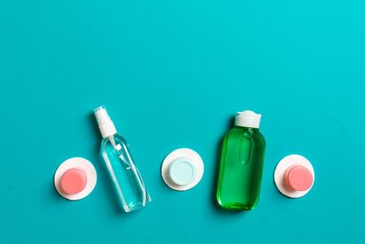 Group of small bottles for travelling on colored background. Copy space for your ideas. Flat lay composition of cosmetic products. Top view of cream containers with cotton pads photo