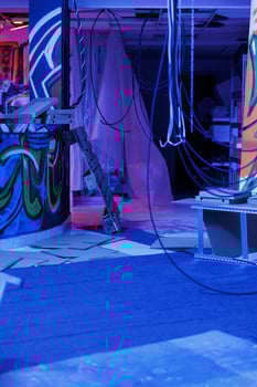 Rusty abandoned warehouse covered in graffiti art, artwork illuminated by purple fluorescent bright lights. Urban neglected ghetto filled with garbage, damaged messy building with neon lights. photo