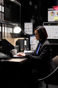 Professional administration businesswoman inserting bookkeeping administrative data paperwork on laptop. Accountancy storage room office filled with folders and diagram charts photo