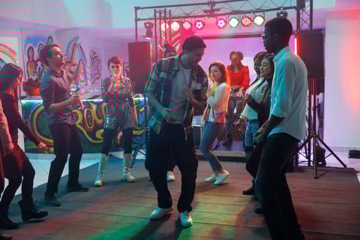 Friends group dancing in nightclub during electronic music live performance. Diverse young men and women having fun, relaxing and moving on dancefloor in crowded club at night photo