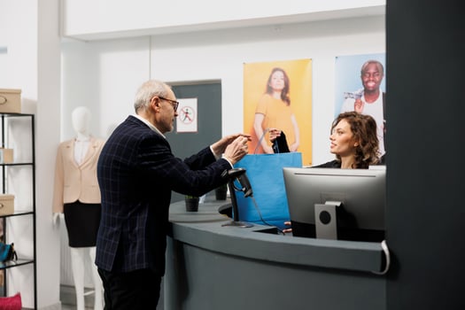 Senior customer taking shopping bag from boutique worker, after buying fashionable clothes in shopping centre. Elderly shopper paying for stylish merchandise during commercial activity photo