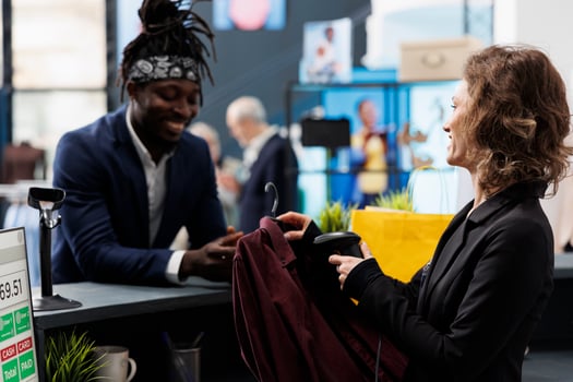 Elegant customer talking with manager at cash register, making transaction on pos terminal in shopping center. Boutique employee scanning shirt using store scanner, commercial activity. photo