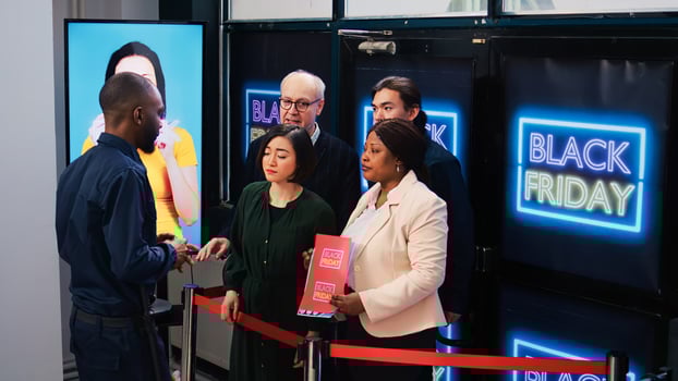 Anxious customers in line for deals on black friday, standing behind red tape at clothing store entrance. Impatient shoppers waiting for opening shop to start promotional shopping spree photo