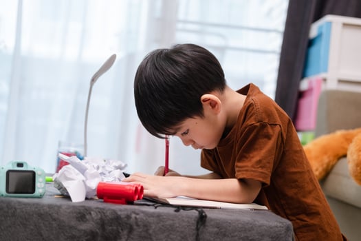Asian boy drawing on table And there was a piece of paper left on the table. photo