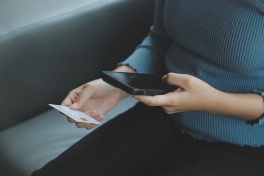 A credit card in the hands of a young businesswoman pays for a business on a mobile phone and on a desk with a laptop. photo