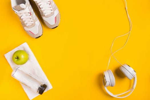 Athlete's set with female clothing, headphones and bottle of water on yellow background photo