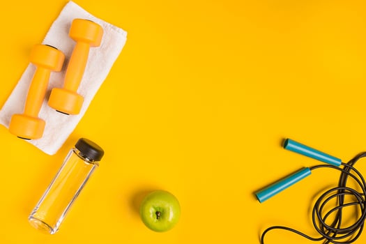 Athlete's set with female clothing, dumbbells and bottle of water on yellow background photo