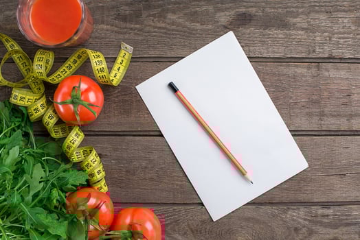 Glass of tomato juice with vegetables and measuring tape on table close-up photo