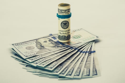 A coiled 100 dollar bill which rests on another angled 100 dollar bill isolated on white background photo