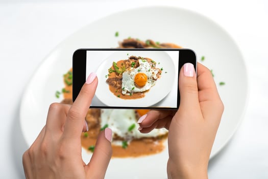 Shooting food on phone's camera, Fried eggs on a white plate with mushroom on a white table, Food Photographer. photo