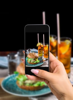 Photographing food concept - woman takes picture of sandwich with chicken burger, cheese and lettuce photo