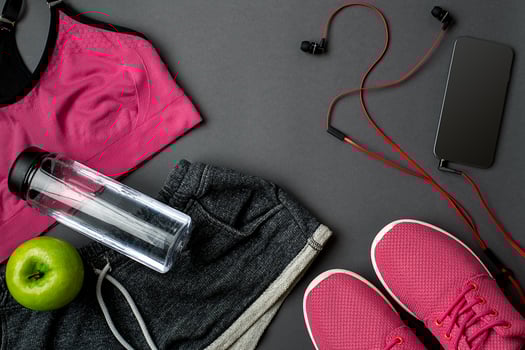 Athlete's set with female clothing, sneakers and bottle of water on gray background photo