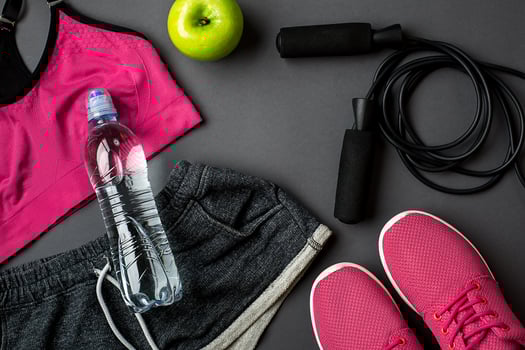 Athlete's set with female clothing, sneakers and bottle of water on gray background photo