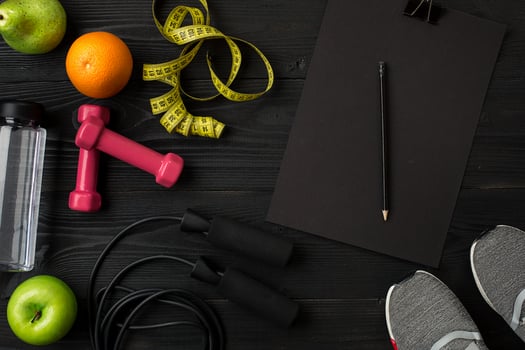 Athlete's set with female clothing, sneakers and bottle of water on dark background photo