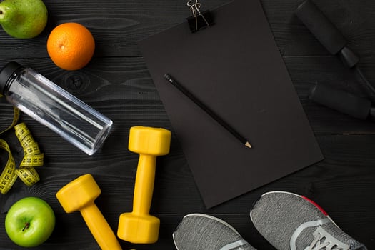 Athlete's set with female clothing, sneakers and bottle of water on dark background photo