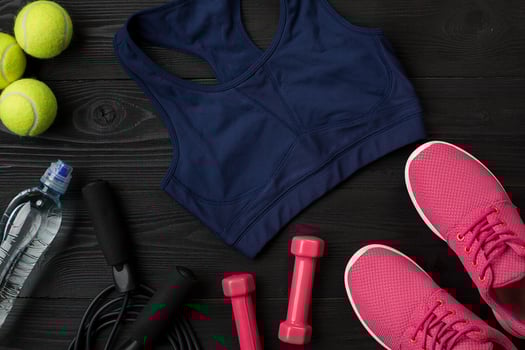 Athlete's set with female clothing, sneakers and bottle of water on dark background photo