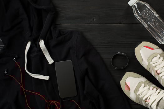 Athlete's set with female clothing, sneakers and bottle of water on dark background photo