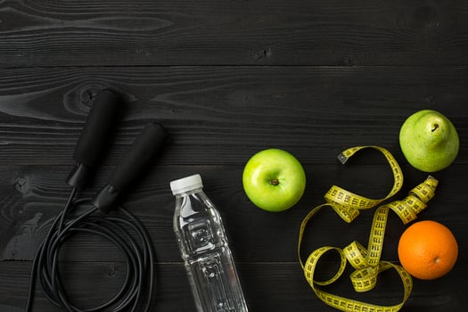 Athlete's set with female clothing, sneakers and bottle of water on dark background photo