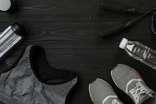 Athlete's set with female clothing, sneakers and bottle of water on dark background photo