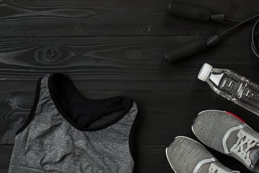 Athlete's set with female clothing and bottle of water on dark background photo
