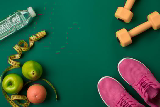 Athlete's set with female clothing and bottle of water on green background photo