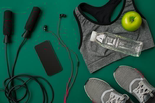 Athlete's set with female clothing and bottle of water on green background photo