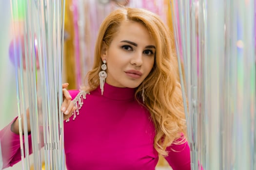 Studio photo of shiny blond woman in sexy pink dress. Perfect wavy hairs. New year  party.