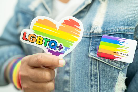 Asian lady wearing rainbow flag wristbands and hold red heart, symbol of LGBT pride month celebrate annual in June social of gay, lesbian, bisexual, transgender, human rights. photo
