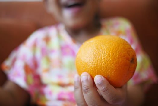 child holding a slice of orange fruit photo