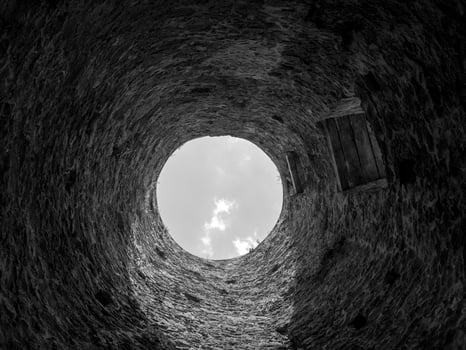 Stone well hole, old construction from inside, brick walls and blue sky background, fall down in the well concept photo