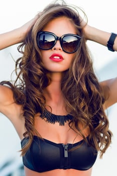 Close up fashion  summer  portrait of stylish  sexy  woman with perfect  tanned fit body   wearing trendy sunglasses drinking cocktail and  enjoying  pool party on luxury villa. photo