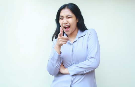 young beautiful business woman pointing finger to camera with excitement folded arm and blink eye dressed formal shirt isolated on white photo