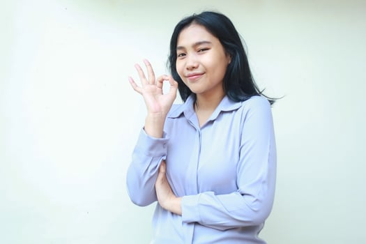happy asian young business woman show ok sign perfection gesture look camera with confidence smile, folded arm female wear formal shirt isolated background photo