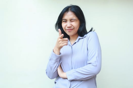 happy successful asian young business woman blink eye and pointing to camera with thumbs up standing confidence over isolated white background, wear formal shirt photo